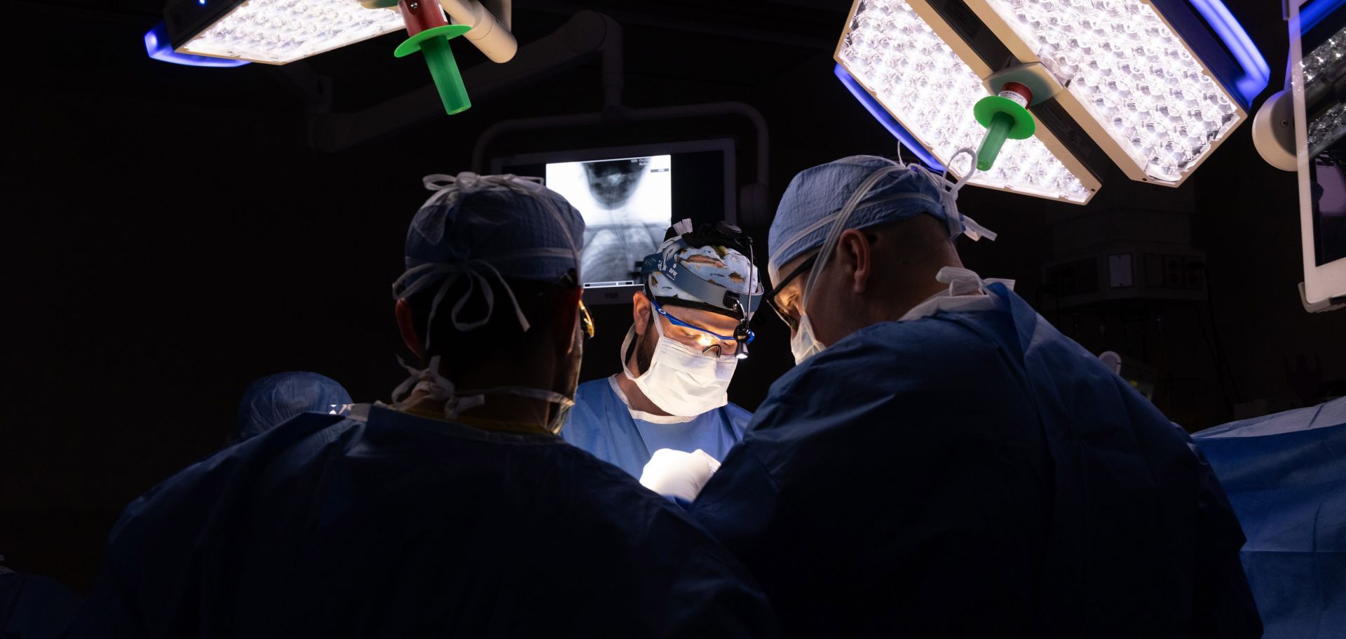 Dr. Tyler McDonald, pediatric orthopaedic surgeon and an assistant professor of orthopaedic surgery, center, and Dr. Richard Menger, chief of complex spine surgery and associate professor of neurosurgery, right, perform surgery at USA Health Children’s & Women’s Hospital in August 2023 to insert pins into Abby Flowers' skull for halo gravity traction.